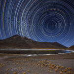 Science and art unite in this beautiful photograph, taken in Chile’s Atacama Desert by ESO Photo Ambassador Adhemar M. Duro Jr. To create this visual masterpiece Adhemar pointed his camera at the sky’s south pole, the point at the centre of all the bright arcs and circles. All the stars in the night sky revolve around this point. Over a period of several hours, this motion creates star trails, with each individual star tracing out a circle on the sky. These trails display the various brightnesses and colours of each star, creating a captivating scene! Towards the top left of the image, you can see a short, bright streak of light cutting across the trails — this is caused by a meteor, burning up in a flash of light as it enters Earth’s atmosphere. The desert’s harsh and arid landscape, illuminated here by the light from the stars themselves, is the perfect place to view the night sky. Because of the location’s favourable conditions several telescopes are hosted here, including ESO’s Very Large Telescope, ESO’s Visible and Infrared Survey Telescope for Astronomy (VISTA), and the forthcoming European Extremely Large Telescope, which is currently under construction atop Cerro Armazones.
